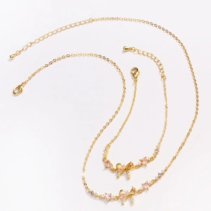 Detail of gold bow necklace and bracelet set with pink zircon and adjustable lobster clasp
