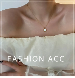 Close-up of golden necklace with white shell pendant on model's neck for elegant look
