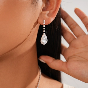 Detail of silver drop earrings featuring pear-cut crystals and a linear pavé diamond design