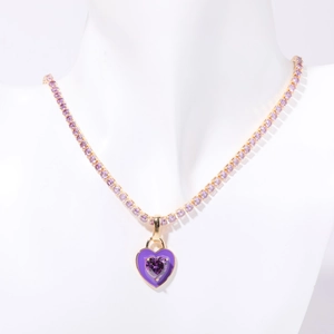 Detail of a purple zircon heart pendant on a gold tennis chain around a white neck model
