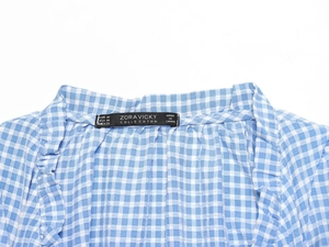 Close-up detail of the ZORAVICKY blue and white plaid shirt collar and brand size label