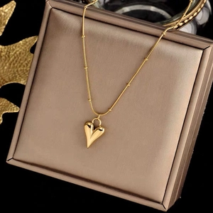 Macro detail of luxury gold heart pendant necklace inside a shimmering metallic jewelry box