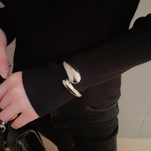 Close-up of polished silver liquid metal teardrop cuff bracelet on a model wrist