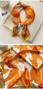 Macro detail of orange silk scarf featuring vintage deer prints and artistic floral borders