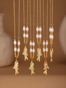 Macro shot of colorful enamel koi fish pendants with pearls on gold-plated chains