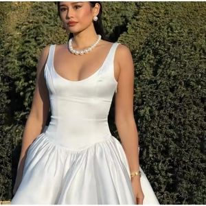 Détail de la texture de la robe de soirée en satin blanc et du collier de perles larges
