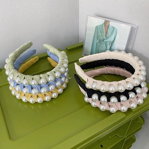 Detail showing colorful fabric headbands with large artificial pearls in a neat stack