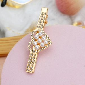 Gros plan sur une barrette dorée avec des strass brillants et un motif cœur en perles