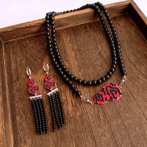 Detail of red gourd pendants on black beaded necklace and tassel earrings set