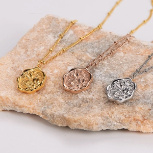Three minimalist flower embossed necklaces in gold, rose gold, and silver finishes