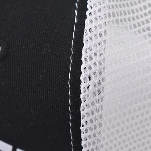 Detailed close-up of stitching on black fabric and white honeycomb mesh trucker hat