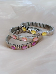 Close-up of three stretch stainless steel bracelets with pink, yellow, and purple stones