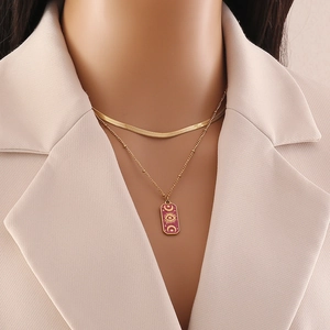 Close-up of layered gold snake chain and burgundy star moon pendant on a model
