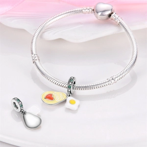 Detail of silver snake chain bracelet featuring enamel avocado charms and engraved text