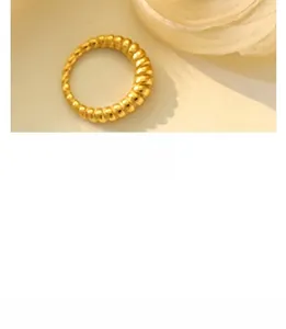 Macro shot of gold-plated ribbed texture on a minimalist geometric ring over warm beige
