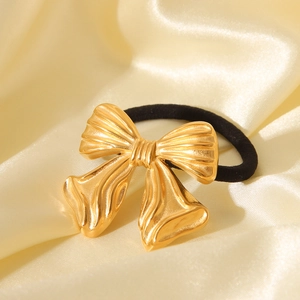Textured 18K gold stainless steel bow hair tie on a luxurious beige silk background