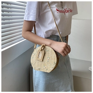 Macro detail of hand-woven straw crossbody bag featuring delicate floral embroidery