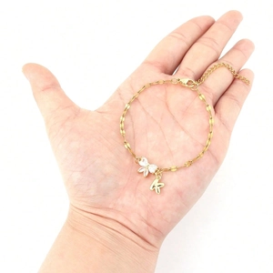 Detailed view of a gold chain bracelet featuring a white rhinestone butterfly and K pendant