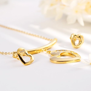 Golden heart necklace and earrings set with crystal accents on a clean white background