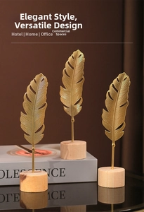 Detail of three golden metal feather ornaments with intricate textures on wood bases
