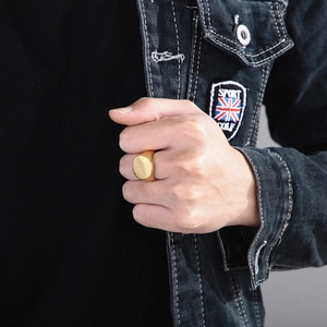 Close-up of a polished gold signet ring for men featuring a minimalist oval face design