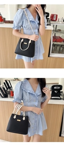 Classic black and white leather handbag with gold buckle shown in a cozy cafe setting