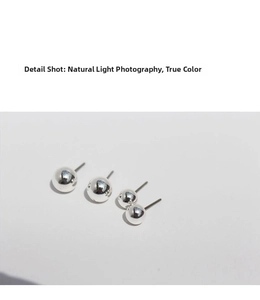 Dettaglio macro di quattro diverse dimensioni di orecchini a sfera in argento S925 lucido