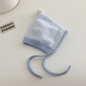Detailed knit texture of light blue baby elf hat with soft pompom and chin straps
