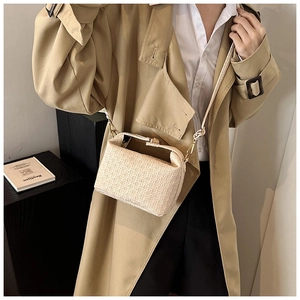 Beige textured crossbody bag with geometric patterns worn with a classic trench coat