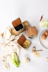 Flat lay of ceramic spice jar set with bamboo lids and spoons on a wooden tray