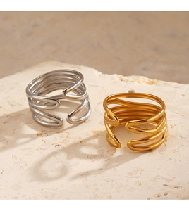 Detail view of 18K gold and silver layered open rings on a textured stone surface
