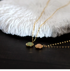 Close-up of round green and pink agate pendants on 18K gold plated steel chains