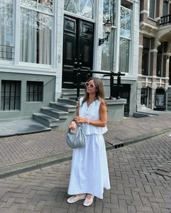 Detail of white pleated sleeveless top and maxi skirt with textured cotton-linen fabric