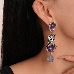 Close-up of vintage resin cat earrings with purple rhinestones worn by a model
