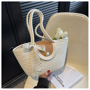 Detail of straw woven bag with brown flap, pearl clasp, and decorative lace bow handle