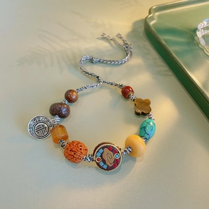 Close-up of ethnic handmade woven bracelet with wooden beads and turquoise on green tray