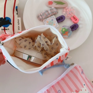 Detailed view of mini fabric pouches with stripes and rabbit patterns showing internal storage