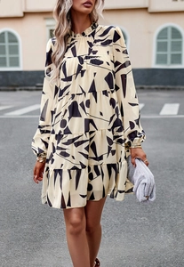 Détail de la robe courte beige à étages avec motifs géométriques noirs et col montant élégant