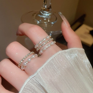 Close-up of golden layered rings set with pearls and rhinestones on fingers