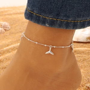Silver bead anklet with whale tail charms worn on a sandy beach setting for summer