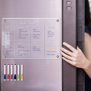Detail of clear magnetic acrylic weekly planner with six colored pens on a fridge