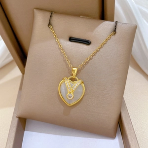 Macro shot of gold heart necklace with white shell inlay and zircon stones in a gift box