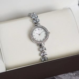 Close-up of luxury mermaid watch with leaf-shaped crystal links and pearl dial in a box