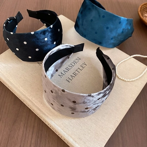 Close-up of three wide velvet headbands with polka dot pattern on book background