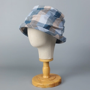 Blue plaid pleated bucket hat for women on a display stand against a gray background