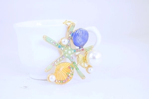Detail of starfish keychain with green enamel and rhinestones on white background