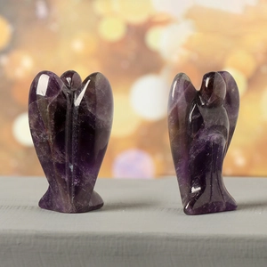 Polished amethyst crystal angel figurines with natural textures on a wooden surface