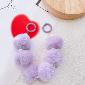 Close-up of purple faux fur pom-poms with white pearls on a stylish decorative chain