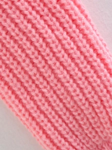Primo piano del tessuto a maglia a coste rosa che mostra texture morbida e cuciture