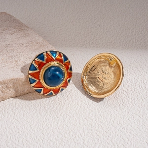 Detail of round vintage earrings showing blue gemstone with colorful enamel and gold metal back